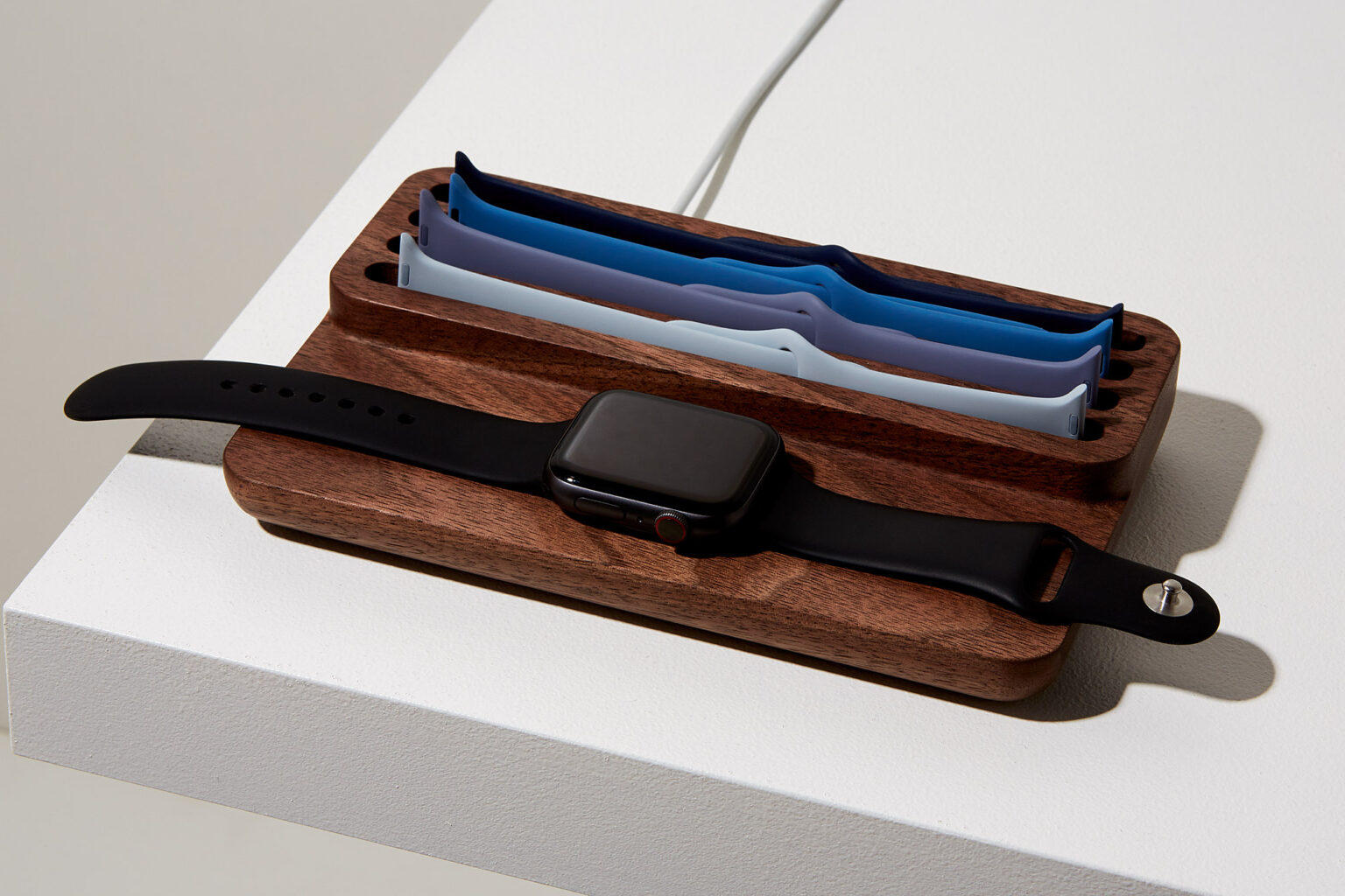 Anden Watch Valet in walnut holding an Apple Watch and spare straps