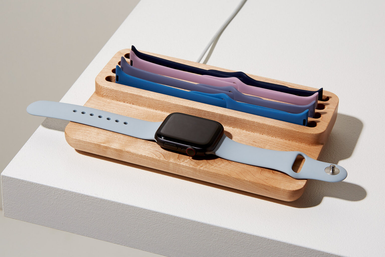 Anden Watch Valet in oak with an Apple Watch charging and spare straps stored in the curved tray