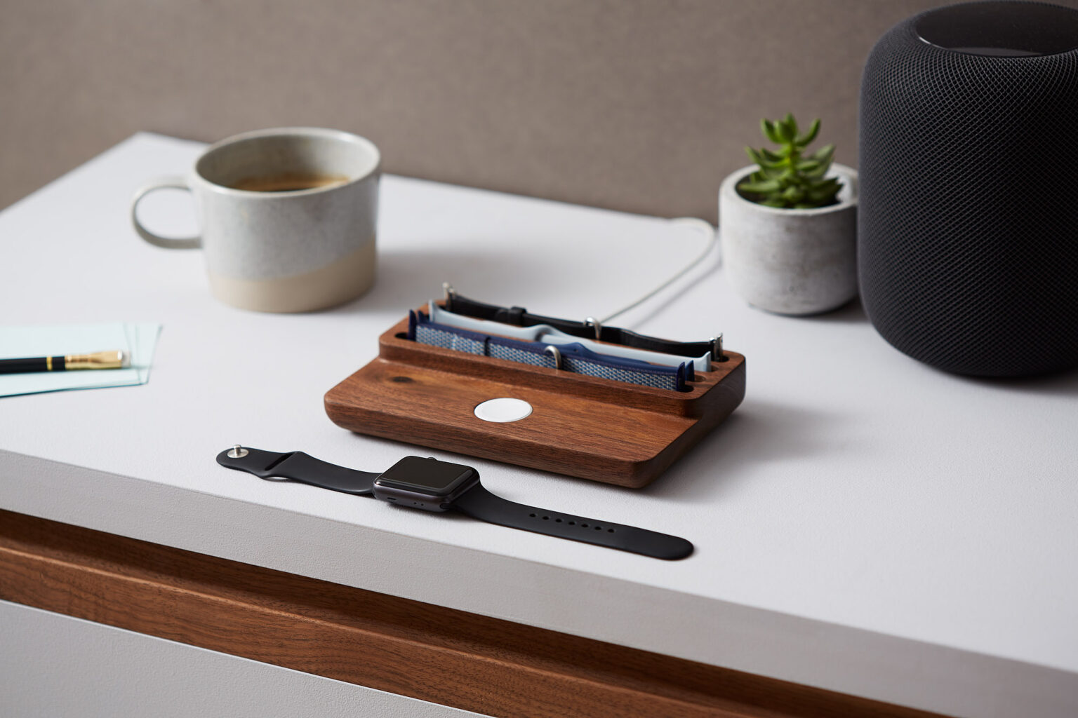 Anden Watch Valet in walnut on a desk beside a mug and a plant