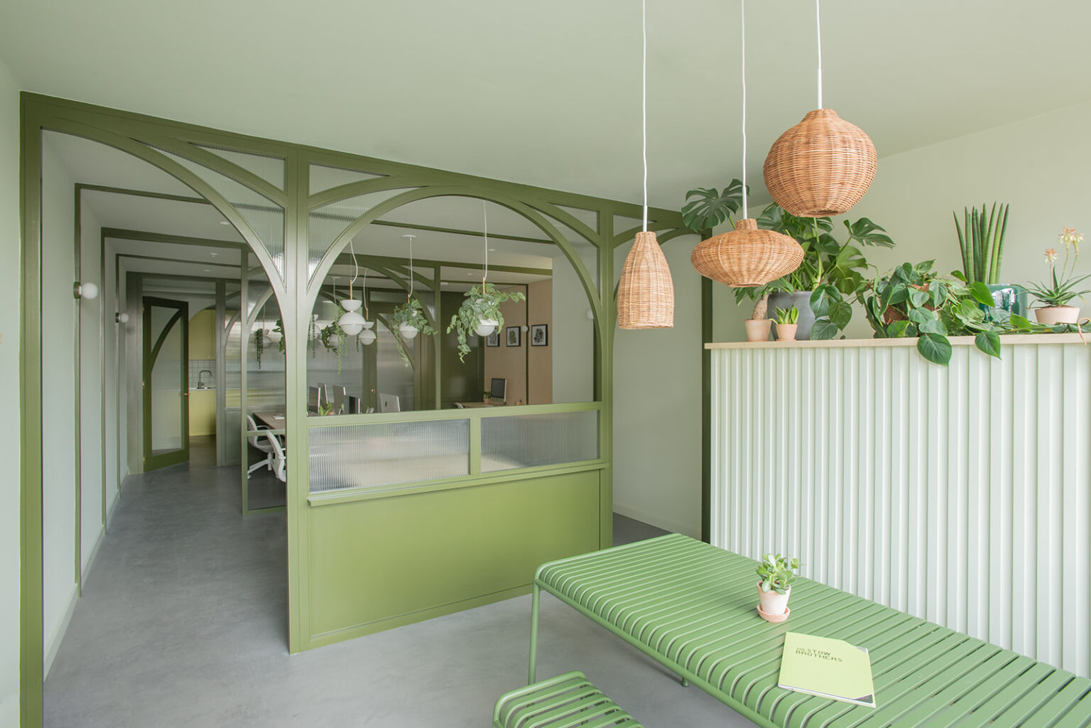 Stow Brothers South Woodford office with green arched partition, pendant lights and seating with a table